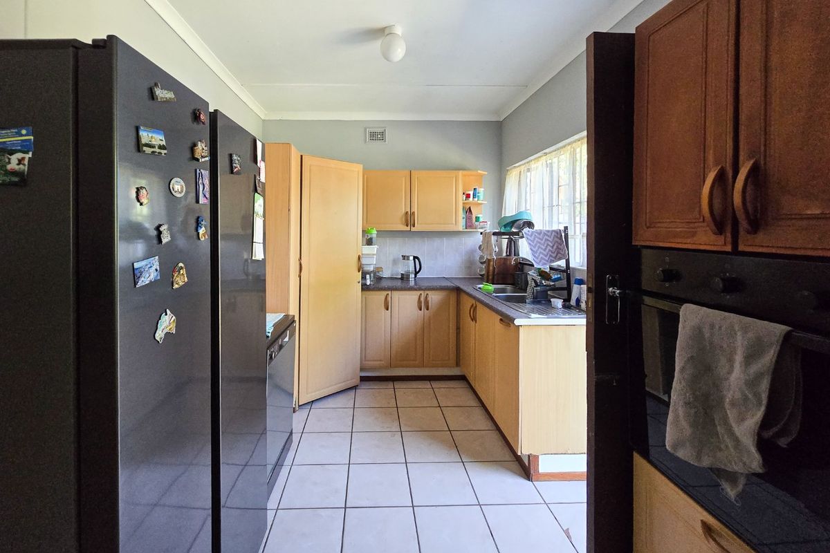 A functional kitchen featuring built-in wooden cabinetry, laminate countertops, a double sink, and tiled flooring, offering a practical layout with potential for modernization.