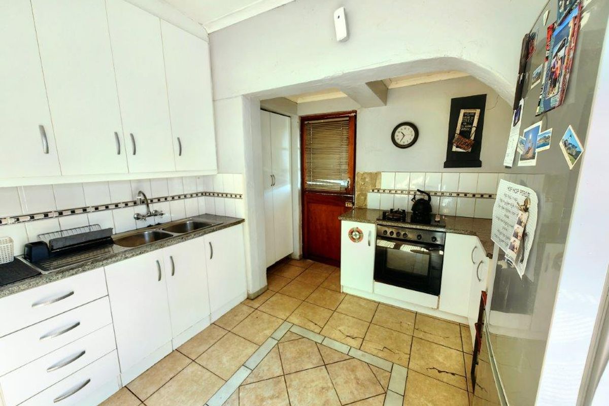 Functional kitchen featuring white cabinetry, tiled flooring, built-in oven and gas hob, with a practical layout and direct access to an exterior door.