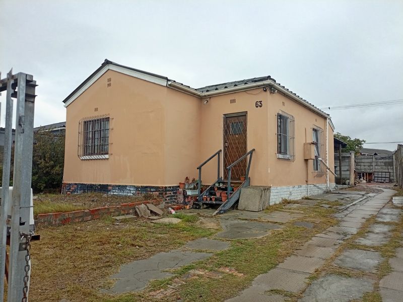 Front elevation of a single-story detached house featuring security bars, metal entrance gate, and concrete stairs, set on a paved and garden plot.