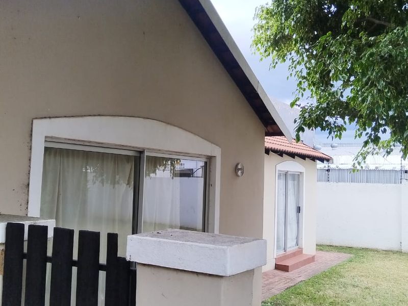 Exterior view of the property featuring a paved walkway, small garden area, and sliding glass doors providing access to the home.