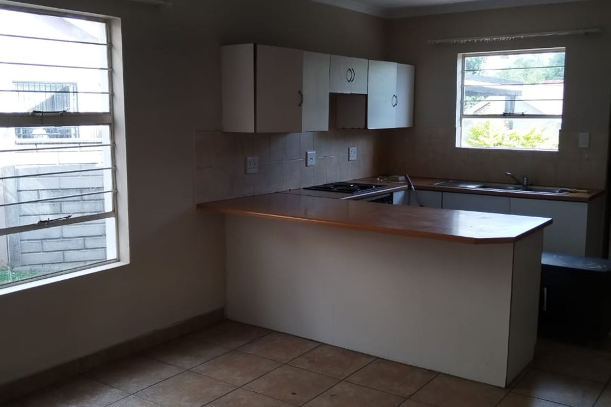 A functional kitchen featuring a breakfast bar, built-in cabinetry, tiled flooring, and large windows providing natural light.