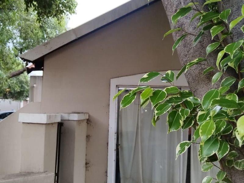 Exterior view of the property featuring a paved patio area, sliding glass doors, and concrete boundary wall elements.