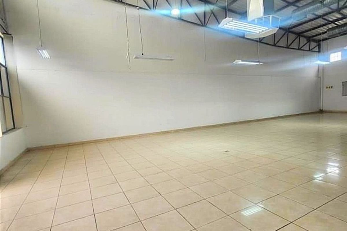 Spacious open-plan commercial area featuring high ceilings with exposed steel trusses, ducted HVAC, and durable ceramic tile flooring, suitable for various business applications.