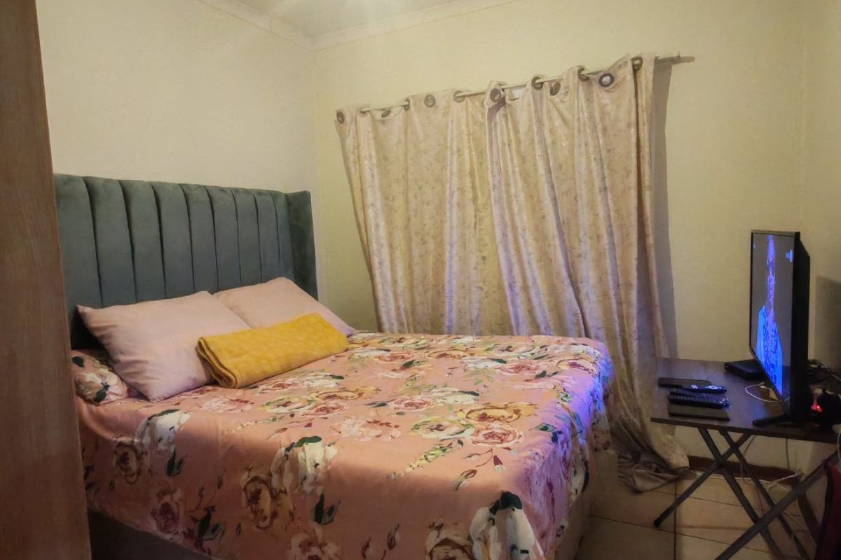 A compact bedroom featuring tiled flooring and a neutral wall finish, providing a functional sleeping space.