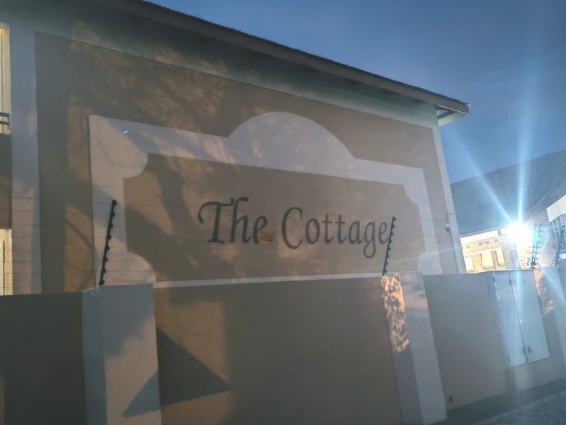 Exterior view of the property entrance featuring a perimeter wall with integrated electric fencing and external lighting at dusk.