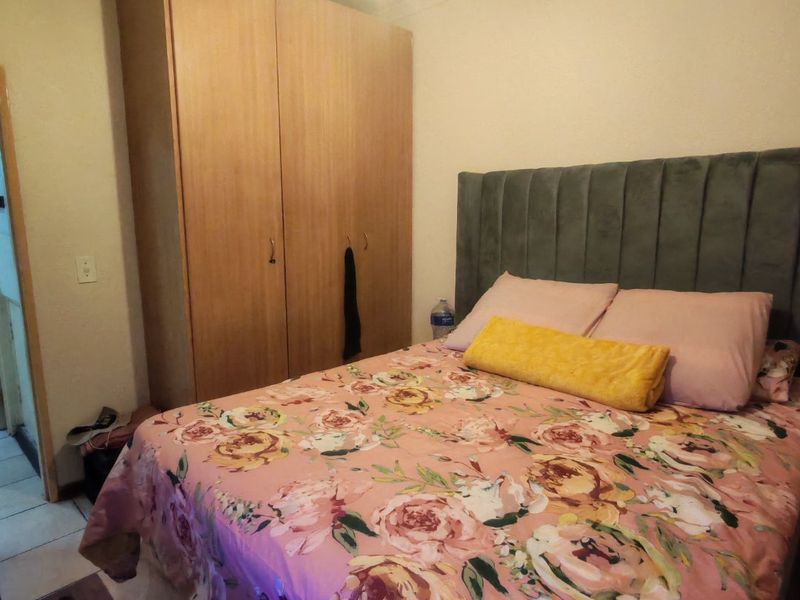 A bedroom featuring a built-in wooden wardrobe and coving detail, providing functional storage space within the room.