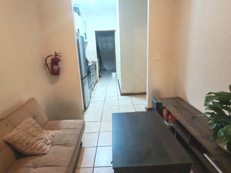 Open plan living area featuring tiled flooring and direct access to the kitchen space, providing a functional layout for daily living.