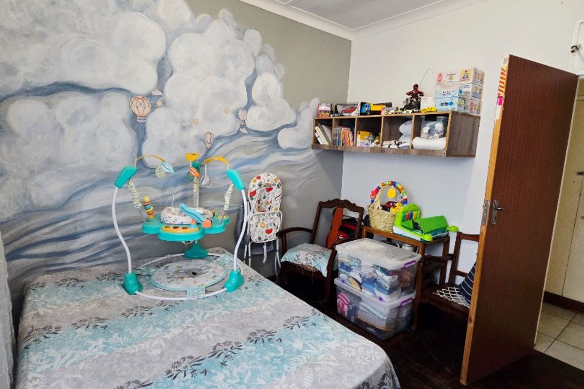 A bedroom featuring parquet flooring, coved ceilings, and built-in wall shelving, currently utilized as a nursery.