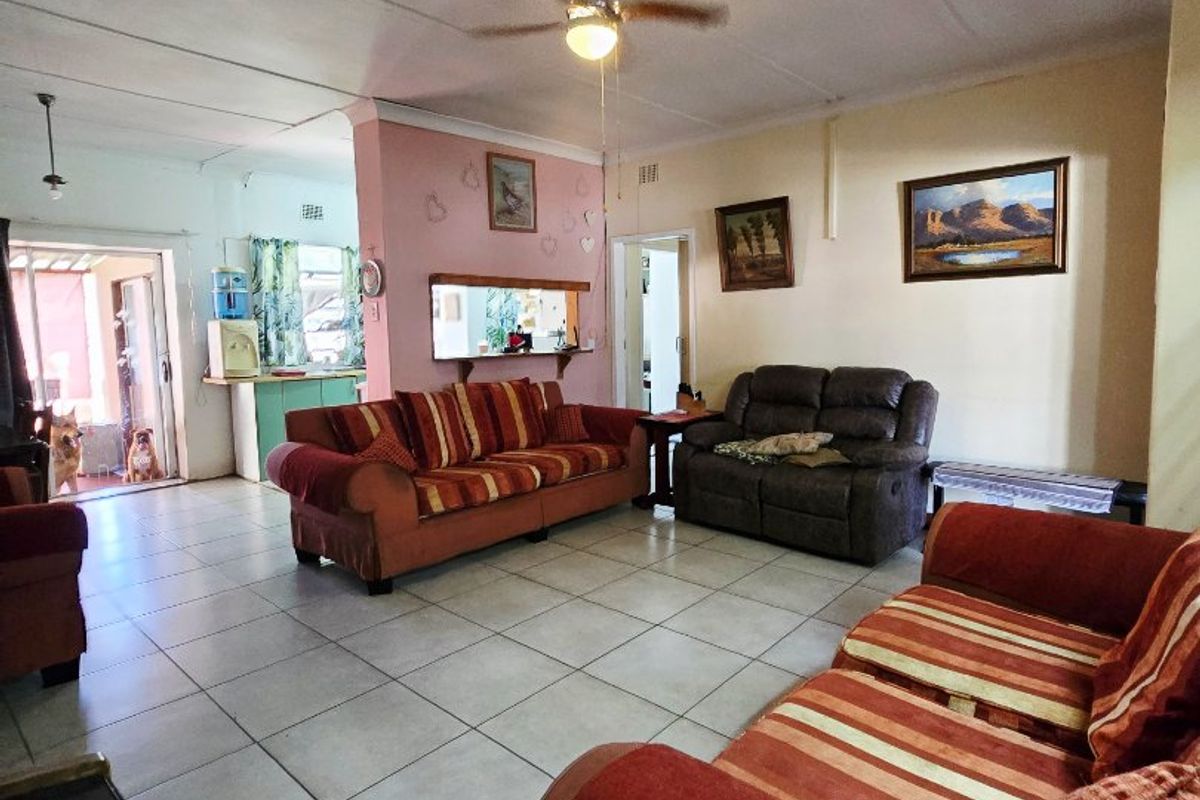 Spacious living room featuring tiled flooring, a ceiling fan, and a convenient pass-through window connecting to the kitchen area.