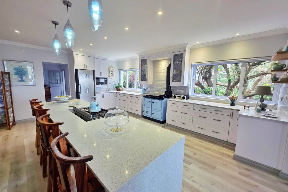 Spacious, modern kitchen featuring a large central island with quartz countertops, ample cabinetry, a vintage-style range oven, and bright recessed lighting.