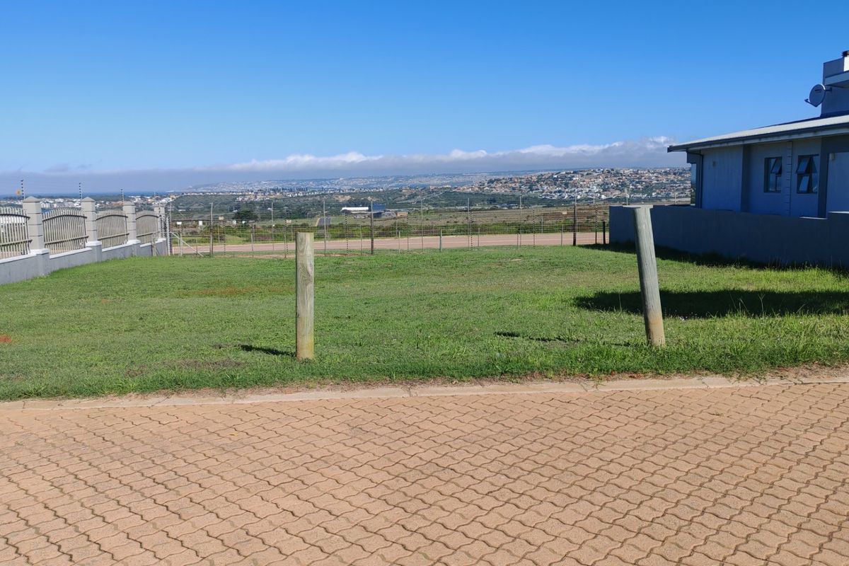 A vacant residential plot featuring a paved driveway, perimeter fencing, and scenic landscape views, offering a clear space for potential development.