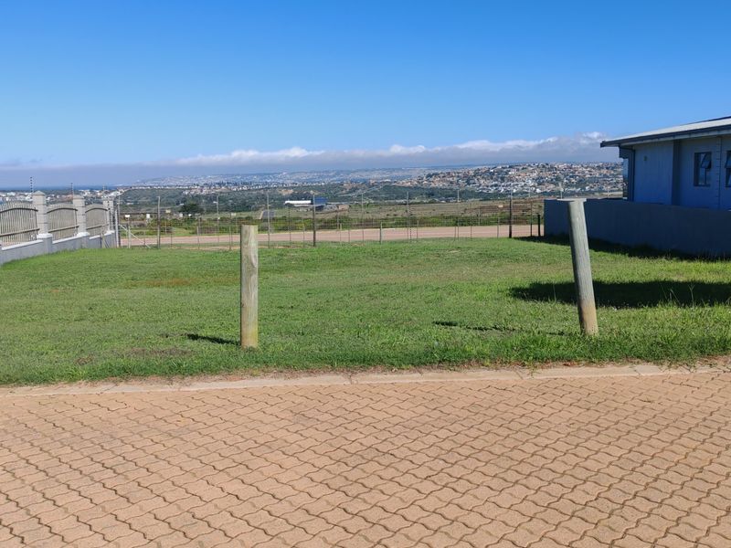 A vacant residential plot featuring a paved driveway, perimeter fencing, and scenic landscape views, offering a clear space for potential development.