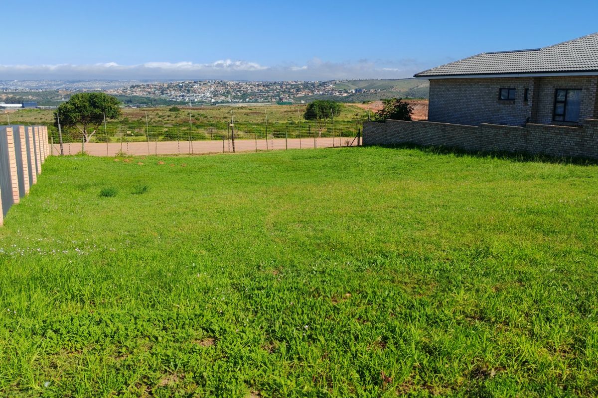 A vacant residential plot featuring a grassy lawn, brick boundary walls, and expansive views of the surrounding landscape and neighborhood.