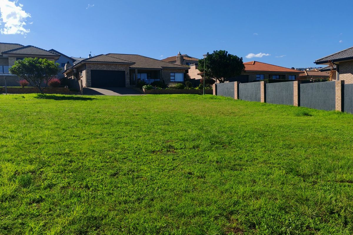 A vacant residential plot featuring a well-maintained grass lawn and established boundary walls, situated in a developed neighborhood.