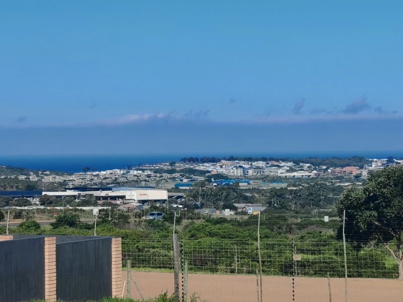 Elevated view overlooking the surrounding coastal landscape and residential area, featuring a secure boundary fence in the foreground.