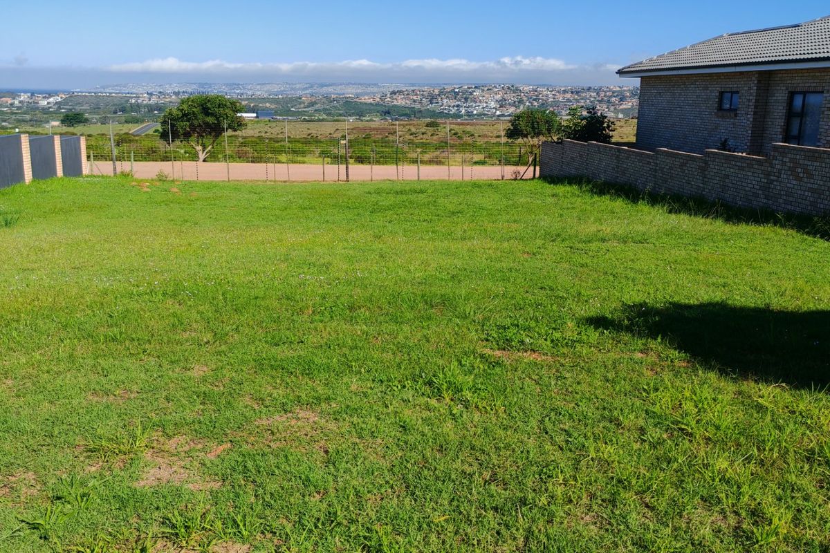 A spacious residential plot featuring a well-maintained grass lawn, enclosed by brick boundary walls and wire fencing, offering scenic views of the surrounding area.