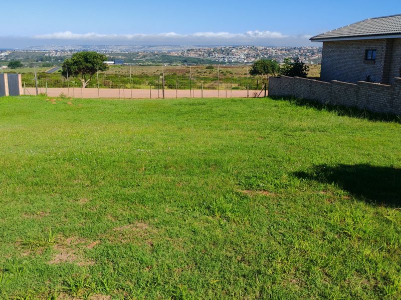 A spacious residential plot featuring a well-maintained grass lawn, enclosed by brick boundary walls and wire fencing, offering scenic views of the surrounding area.