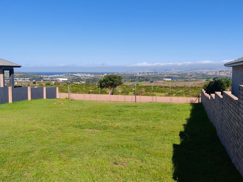 A clear view of the surrounding landscape and distant coastline from the residential property, featuring established brick boundary walls and fencing.