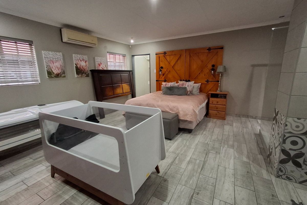 Spacious bedroom featuring modern wood-look tiled flooring, recessed lighting, and an integrated air conditioning unit.