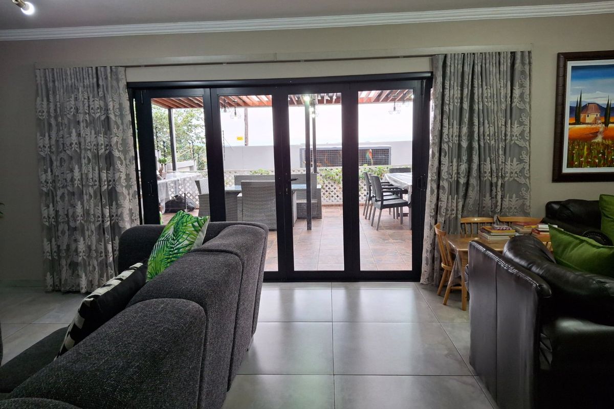 Spacious living area featuring large format floor tiles and black aluminium stacker doors providing seamless access to the outdoor patio.