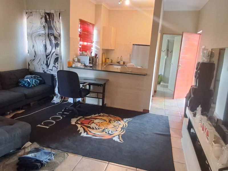 Open plan living area featuring tiled flooring and a breakfast bar connecting to the kitchen space.