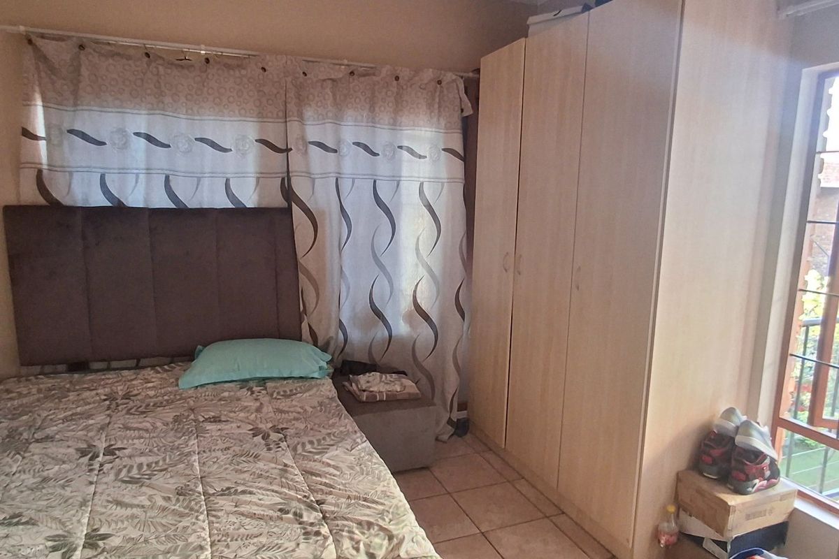 A bedroom featuring tiled flooring and a built-in wardrobe, with natural light provided by a window.