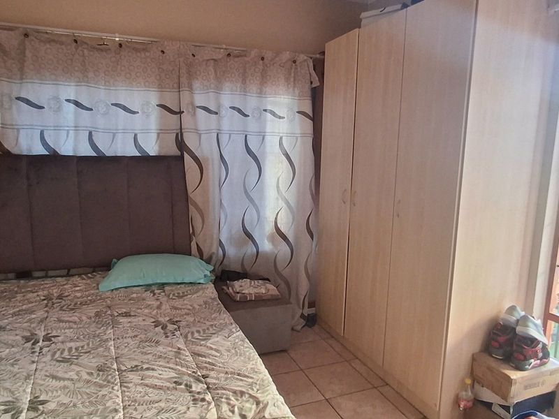 A bedroom featuring tiled flooring and a built-in wardrobe, with natural light provided by a window.