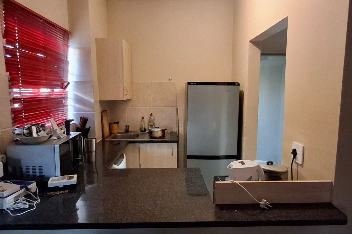 A functional kitchen featuring granite countertops, built-in cabinetry, and a tiled backsplash, offering a practical layout for daily meal preparation.