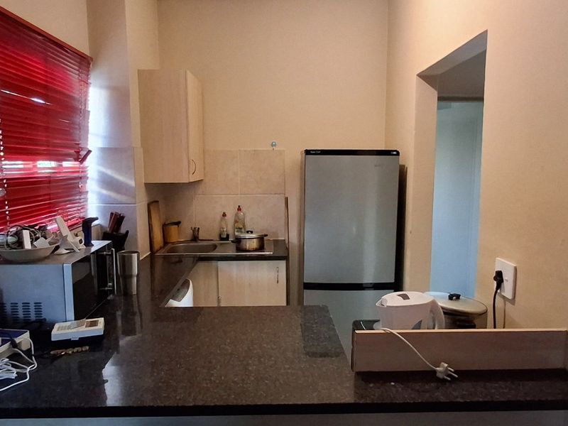 A functional kitchen featuring granite countertops, built-in cabinetry, and a tiled backsplash, offering a practical layout for daily meal preparation.