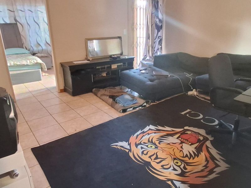 A living room area featuring tiled flooring and access to an adjacent bedroom, providing a functional layout for the apartment.