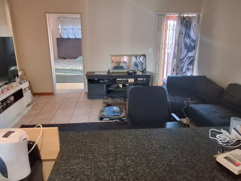 Open plan living area featuring tiled flooring and a kitchen counter, with direct access to an adjacent bedroom and exterior balcony.
