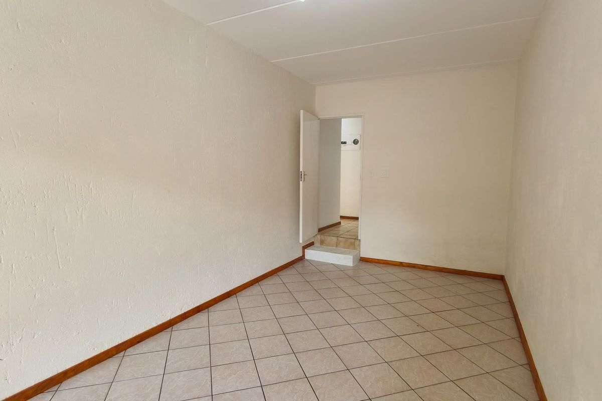 An empty bedroom featuring tiled flooring and neutral walls, providing a blank canvas for personalization.