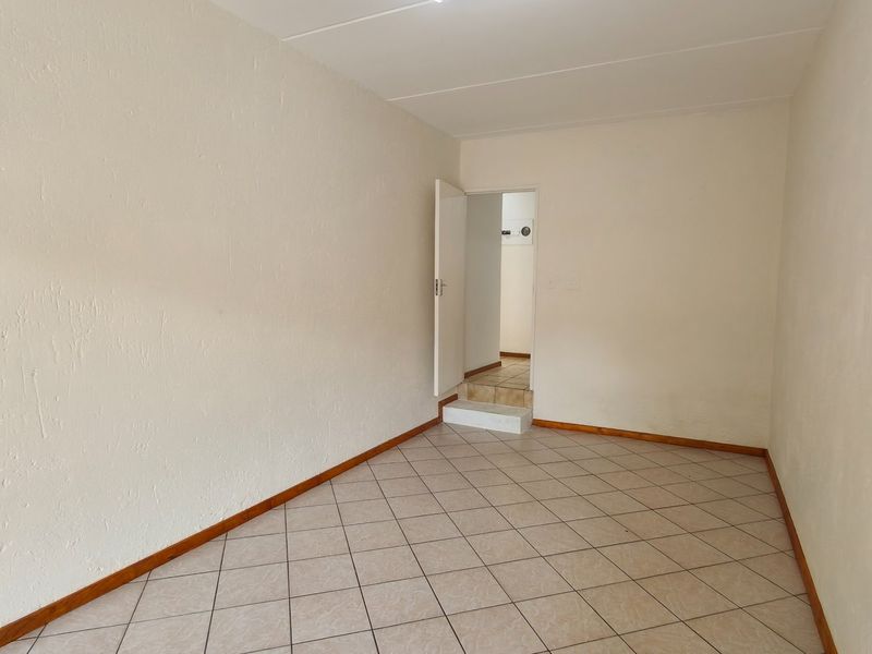 An empty bedroom featuring tiled flooring and neutral walls, providing a blank canvas for personalization.