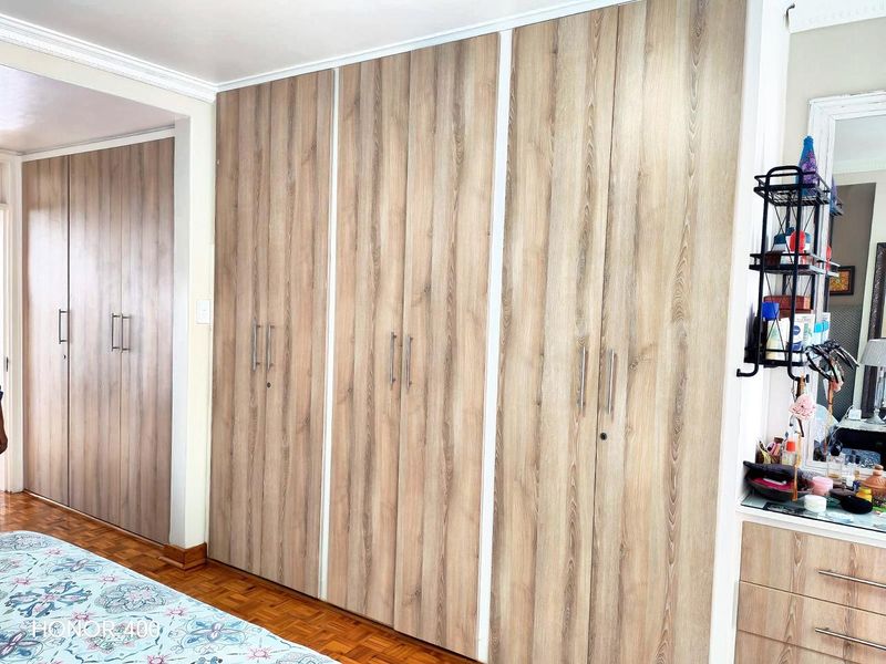 Bedroom featuring extensive floor-to-ceiling built-in wooden wardrobes and classic parquet flooring.
