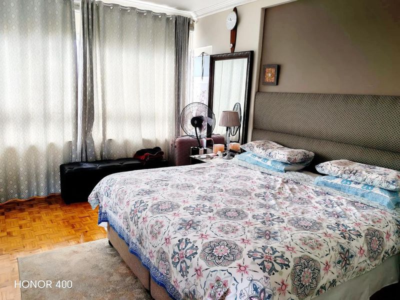 A bedroom featuring parquet flooring and crown molding, with large windows providing natural light.