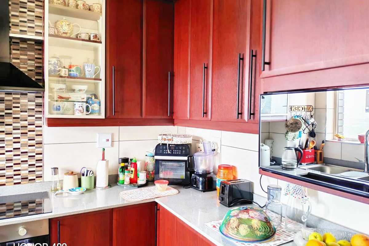 A functional kitchen featuring dark wood cabinetry, stone countertops, a tiled backsplash, and integrated appliances including an oven and extractor fan.