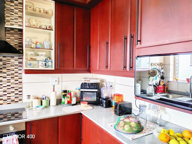 A functional kitchen featuring dark wood cabinetry, stone countertops, a tiled backsplash, and integrated appliances including an oven and extractor fan.
