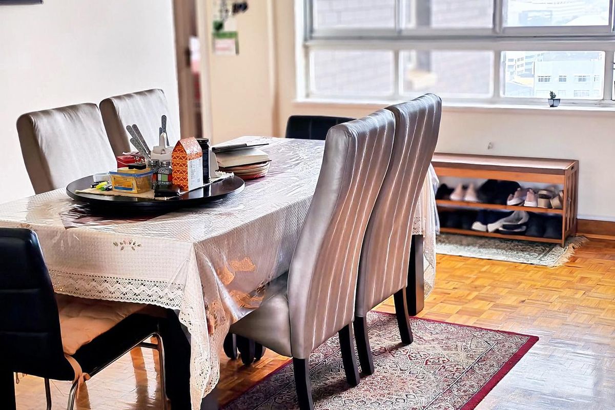 A dining area featuring classic parquet flooring and a large window providing natural light, suitable for family meals and entertaining.