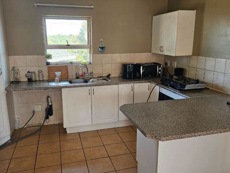 A functional kitchen featuring built-in cabinetry, laminate countertops, a gas hob, and tiled flooring, offering a practical layout for daily meal preparation.