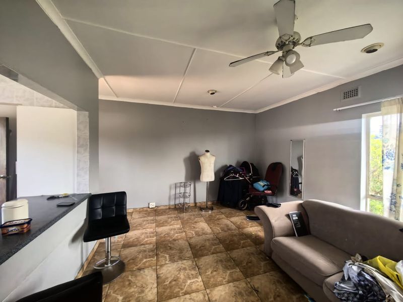 Open plan living area featuring tiled flooring, a ceiling fan, and a breakfast bar counter connecting to the kitchen space.