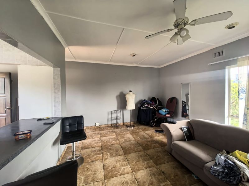 Open plan living area featuring tiled flooring, a breakfast bar, and a ceiling fan, providing a functional space for daily living.