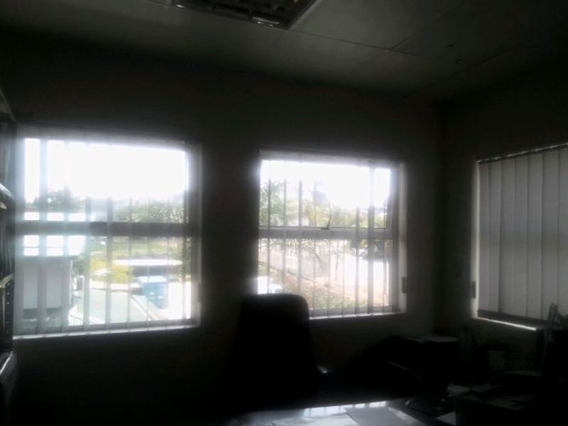 A dimly lit office space featuring multiple casement windows with vertical blinds, providing natural light and exterior views.
