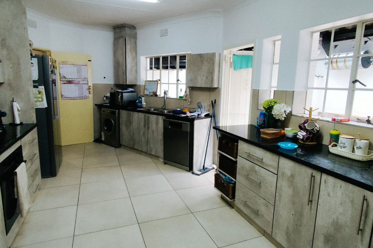 Spacious kitchen featuring dark granite countertops, light wood-look cabinetry, tiled flooring, and integrated appliance spaces with ample natural light.