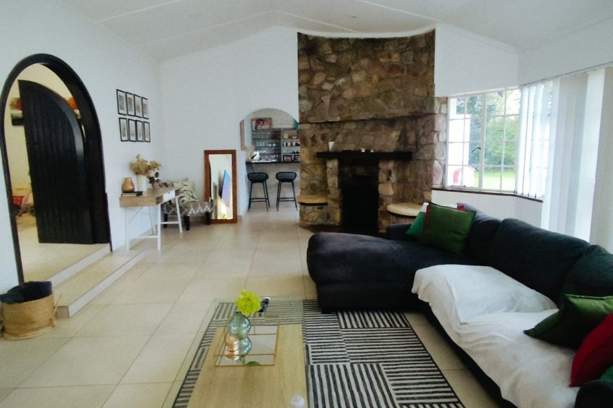 Spacious living area featuring a prominent stone fireplace, vaulted ceilings, tiled flooring, and arched doorways leading to adjacent rooms.