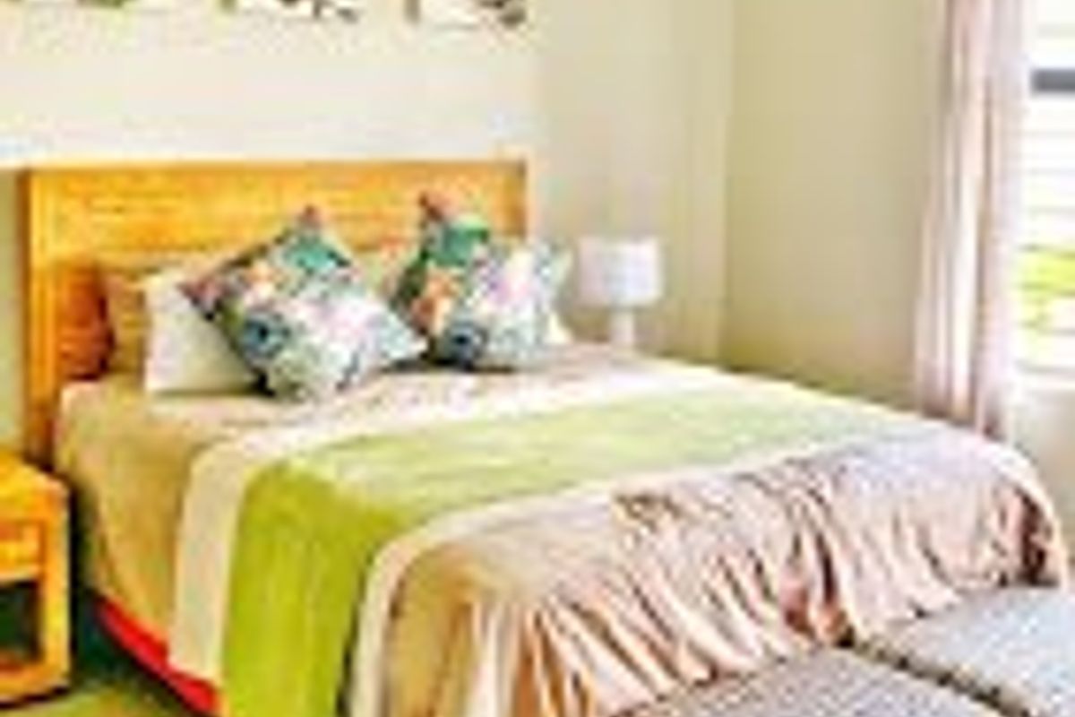 A well-maintained bedroom featuring neutral wall tones, tiled flooring, and natural light through a window with curtain rails.