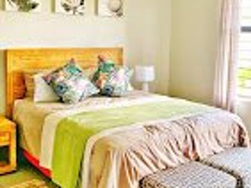 A well-maintained bedroom featuring neutral wall tones, tiled flooring, and natural light through a window with curtain rails.