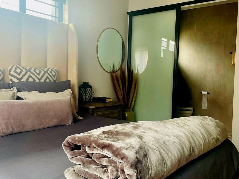 A well-maintained bedroom featuring a modern sliding glass door leading to an en-suite bathroom with tiled finishes.