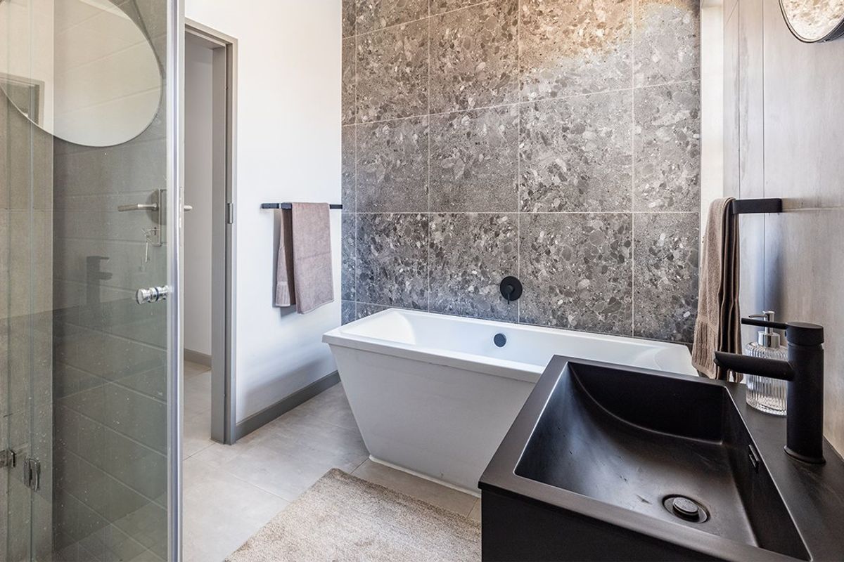 Modern bathroom featuring a sleek freestanding bathtub, a walk-in shower with glass enclosure, and a contemporary vessel sink with matte black fixtures.