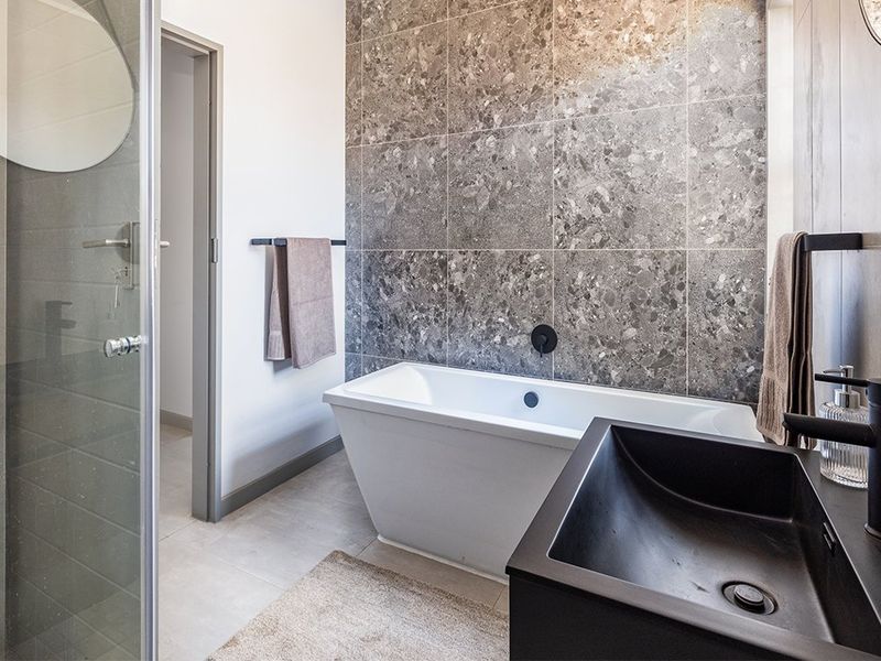 Modern bathroom featuring a sleek freestanding bathtub, a walk-in shower with glass enclosure, and a contemporary vessel sink with matte black fixtures.