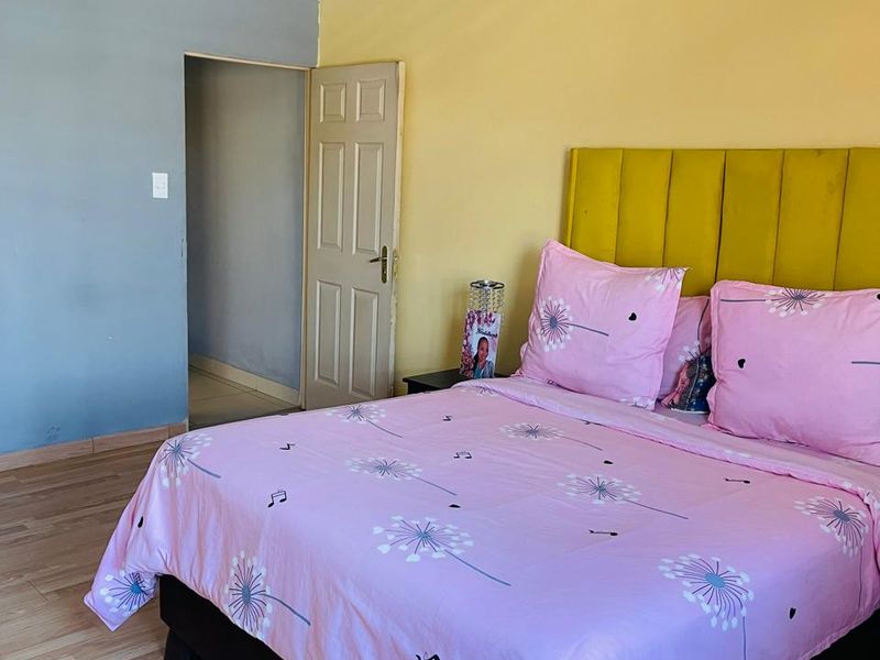 A bedroom featuring laminate flooring, decorative cornice, and a panelled door, with dual-tone wall paint.